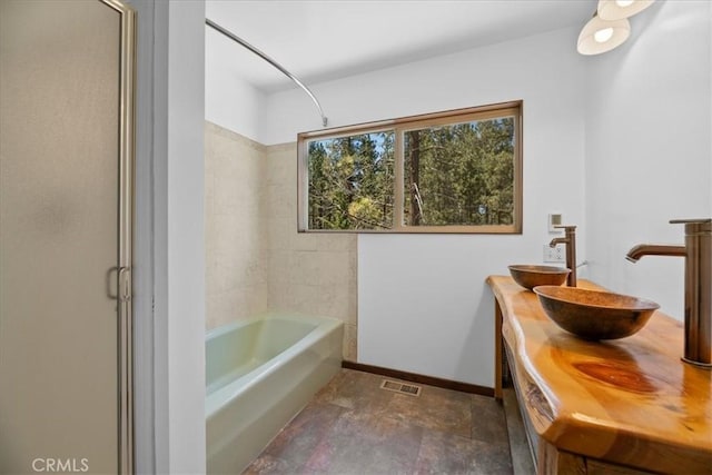 full bathroom featuring a sink, baseboards, double vanity, and visible vents