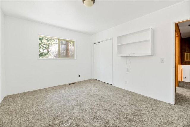 unfurnished bedroom featuring visible vents, carpet flooring, and a closet