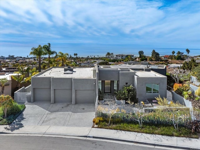 view of front of property with concrete driveway, stucco siding, an attached garage, and fence private yard