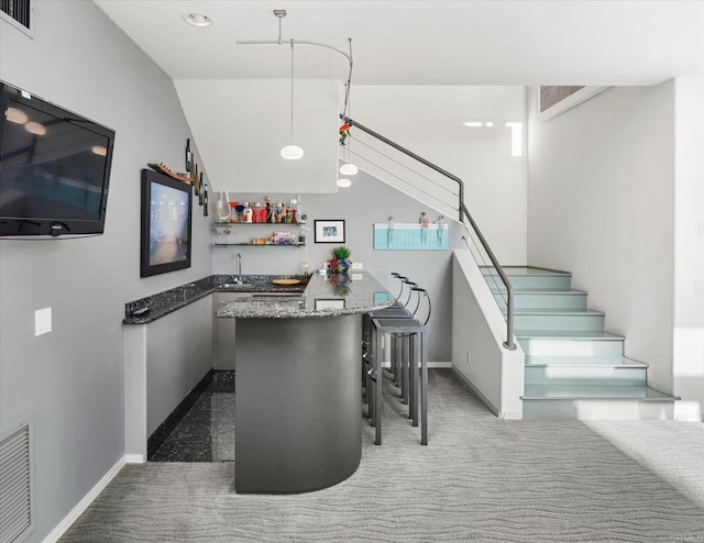 staircase with carpet floors, wet bar, visible vents, and baseboards