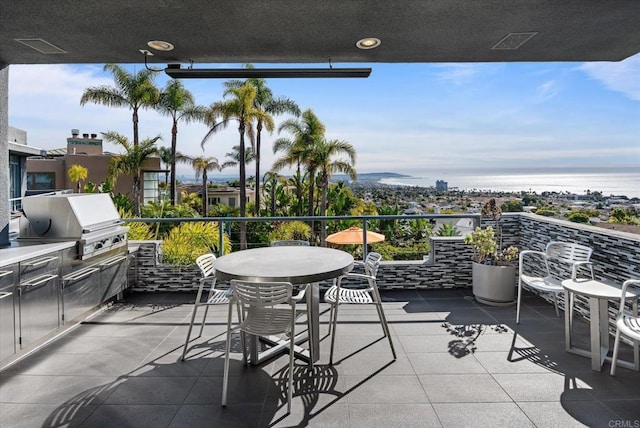 balcony featuring a water view, an outdoor kitchen, and a grill