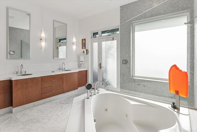 full bathroom with a sink, plenty of natural light, and a tub with jets