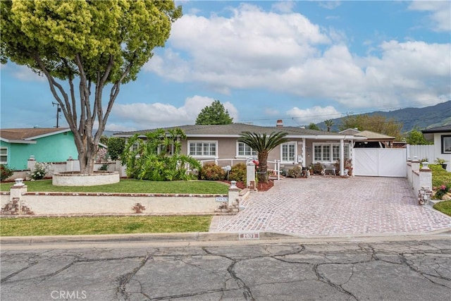 single story home with driveway, a gate, fence, a front lawn, and stucco siding