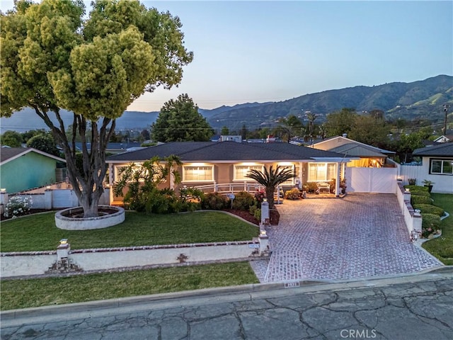 ranch-style house featuring a mountain view, driveway, a front yard, and fence