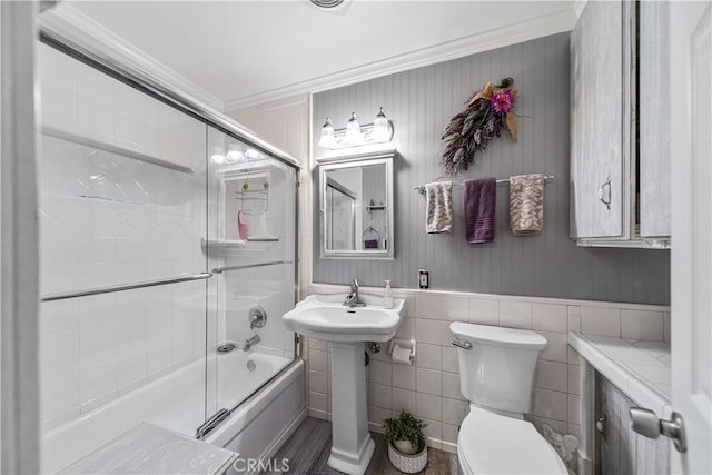 full bathroom with crown molding, tile walls, enclosed tub / shower combo, and toilet