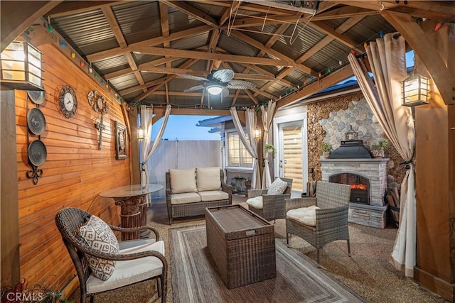 view of patio featuring a gazebo, fence, a ceiling fan, and an outdoor living space with a fireplace