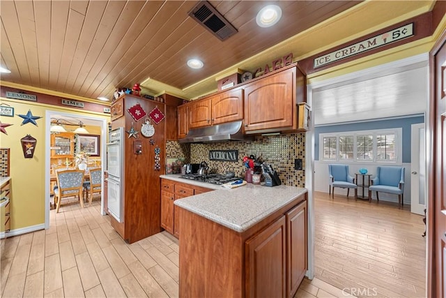 kitchen with visible vents, light countertops, under cabinet range hood, white double oven, and light wood-style flooring