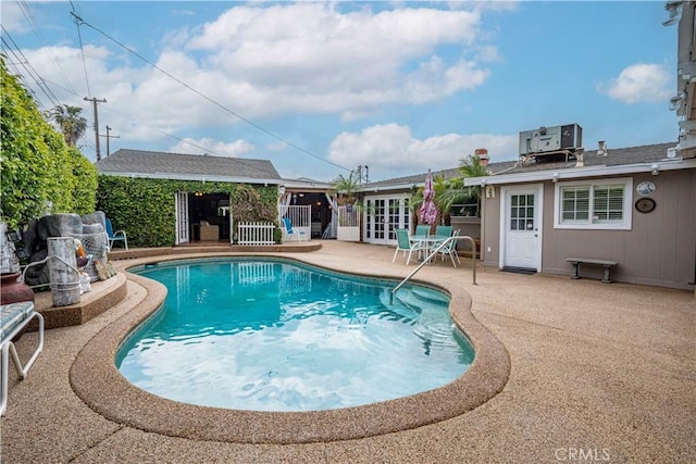 outdoor pool featuring a patio, central AC unit, and french doors
