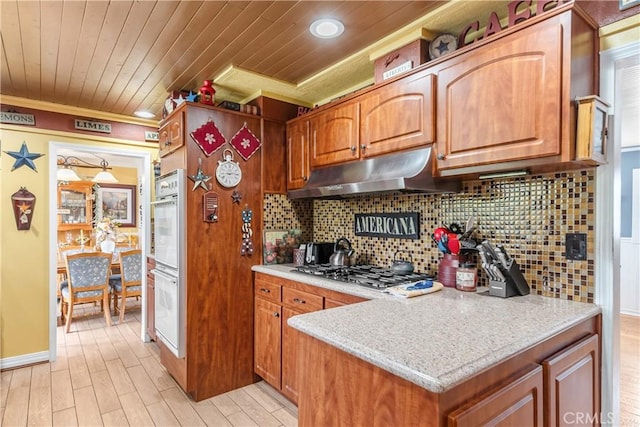 kitchen featuring light wood-style floors, backsplash, stainless steel gas stovetop, ornamental molding, and under cabinet range hood