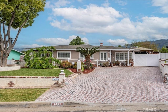 ranch-style house with fence, a front yard, stucco siding, a porch, and driveway