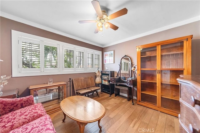 interior space featuring light wood-style floors, crown molding, and a ceiling fan