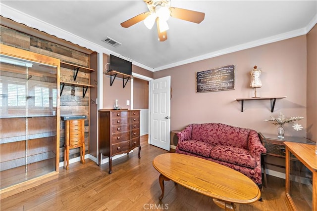 sitting room with crown molding, ceiling fan, baseboards, wood finished floors, and visible vents