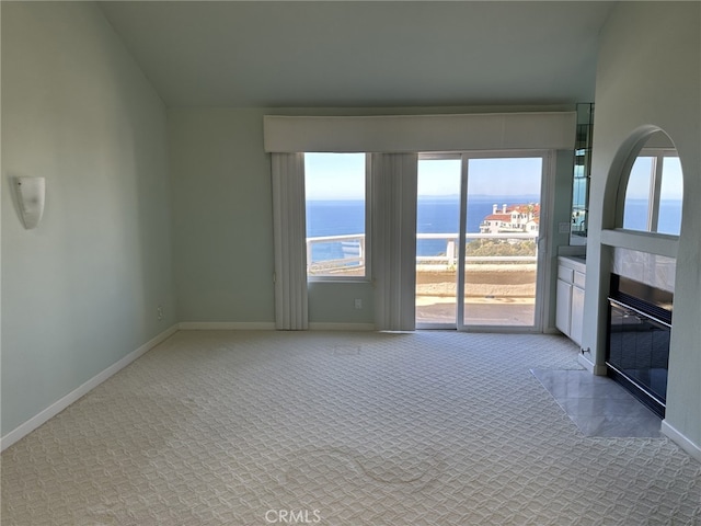 17 Marseille, Laguna Niguel, CA 92677 - interior space with baseboards, a water view, a tile fireplace, carpet flooring, and vaulted ceiling