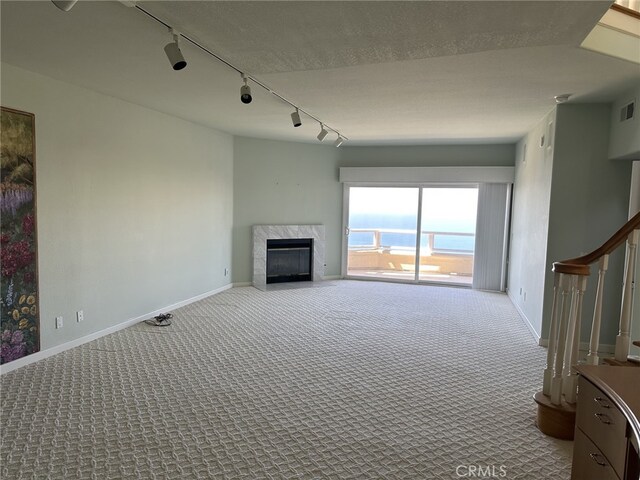 17 Marseille, Laguna Niguel, CA 92677 - unfurnished living room featuring visible vents, track lighting, baseboards, carpet flooring, and a premium fireplace