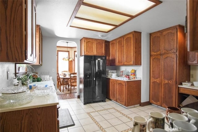 3716 Viader Dr, Modesto, CA 95356 - kitchen featuring black fridge with ice dispenser, a sink, light tile patterned floors, light countertops, and brown cabinets