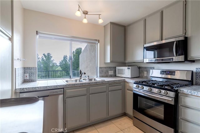 11449 Tampa Ave Unit 139, Porter Ranch, CA 91326 - kitchen featuring light countertops, a sink, light tile patterned floors, gray cabinetry, and stainless steel appliances