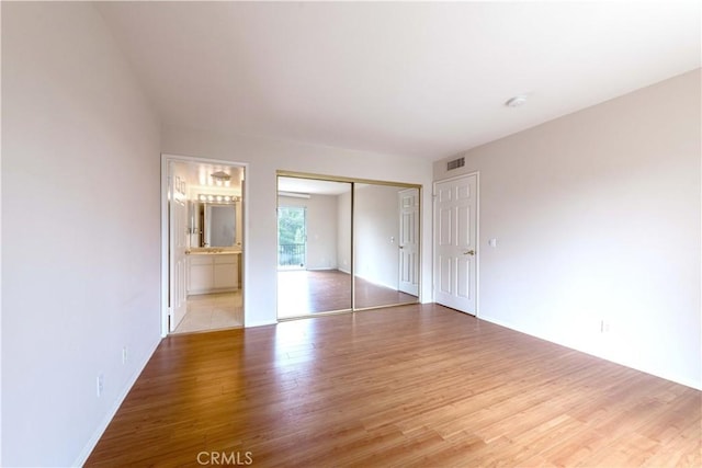 11449 Tampa Ave Unit 139, Porter Ranch, CA 91326 - unfurnished bedroom featuring visible vents, wood finished floors, baseboards, a closet, and ensuite bathroom