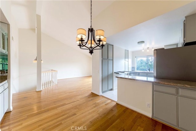 11449 Tampa Ave Unit 139, Porter Ranch, CA 91326 - kitchen with a notable chandelier, light wood finished floors, stone countertops, decorative light fixtures, and lofted ceiling