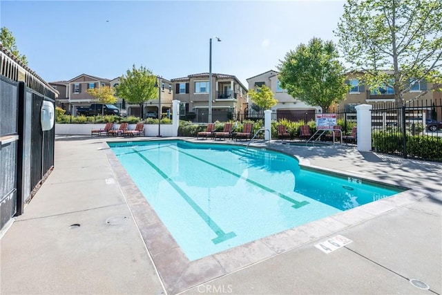 community pool with fence, a residential view, and a patio area