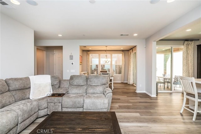 living room with a chandelier, baseboards, visible vents, and light wood finished floors