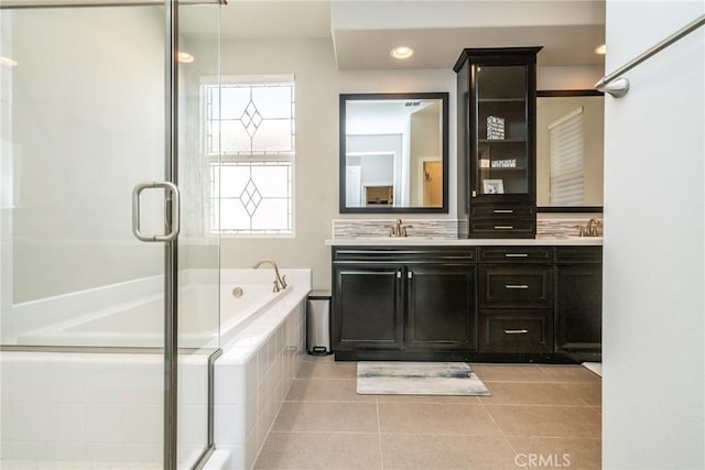 full bathroom featuring tile patterned flooring, double vanity, a relaxing tiled tub, a sink, and a shower with shower door