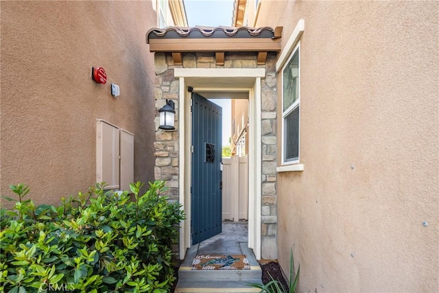 property entrance with stucco siding and stone siding
