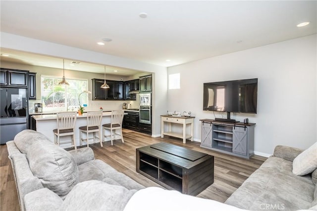 living room featuring recessed lighting, baseboards, and light wood-type flooring