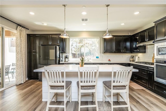 kitchen with visible vents, decorative backsplash, a center island, light countertops, and stainless steel appliances