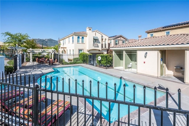 pool with a patio, fence, and a residential view