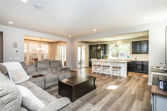 living room featuring recessed lighting, light wood-style flooring, and a notable chandelier