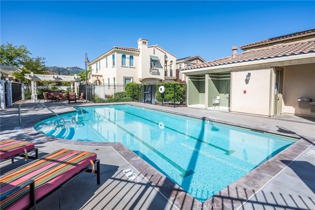 community pool featuring fence, a patio area, and a residential view
