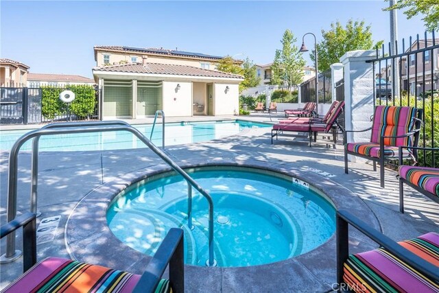 community pool featuring fence, a patio, and a community hot tub