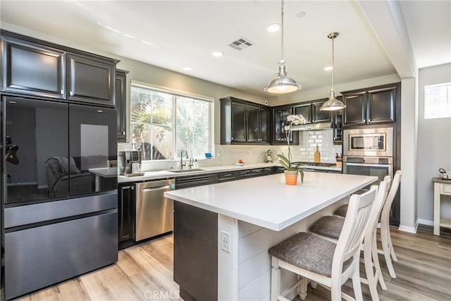 kitchen featuring a breakfast bar area, visible vents, appliances with stainless steel finishes, a sink, and light wood-style flooring
