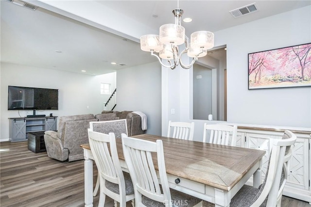 dining room featuring visible vents, wood finished floors, and an inviting chandelier