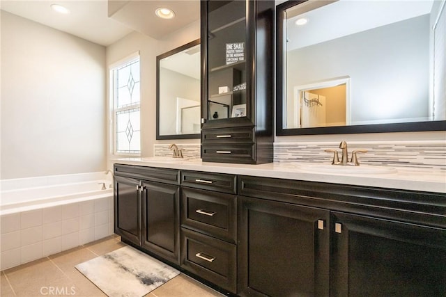 full bathroom featuring a sink, tile patterned floors, double vanity, and a bath