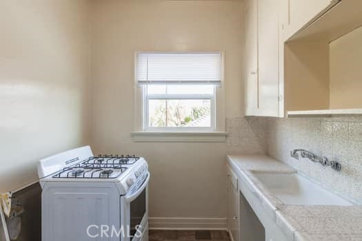 432 N Virgil Ave, Los Angeles, CA 90004 - clothes washing area with baseboards, a sink, and laundry area