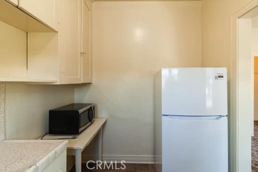 432 N Virgil Ave, Los Angeles, CA 90004 - kitchen with freestanding refrigerator, white cabinetry, black microwave, and light countertops