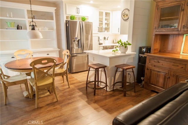 3139 E Chapman Ave Unit 14A, Orange, CA 92869 - kitchen with stainless steel fridge with ice dispenser, light countertops, light wood finished floors, glass insert cabinets, and white cabinetry
