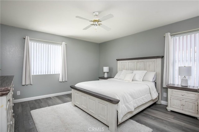 bedroom featuring ceiling fan, baseboards, dark wood-type flooring, and multiple windows