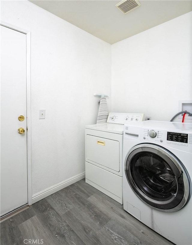 laundry area with washing machine and dryer, wood finished floors, laundry area, visible vents, and baseboards
