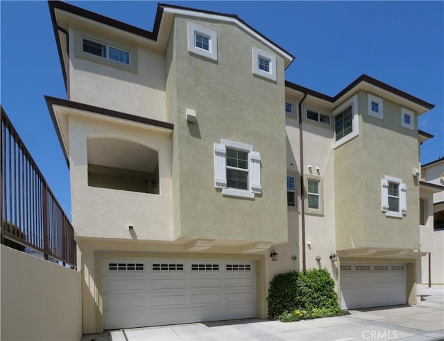 view of front of house with stucco siding, an attached garage, and driveway