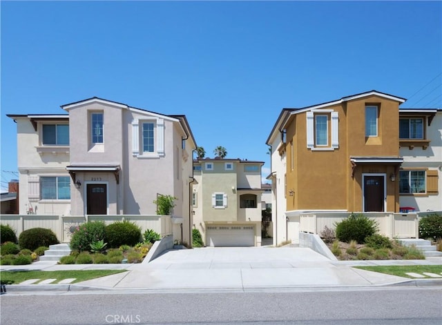 view of front facade featuring a garage, stucco siding, driveway, and fence