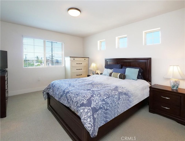 bedroom featuring baseboards, light colored carpet, and multiple windows
