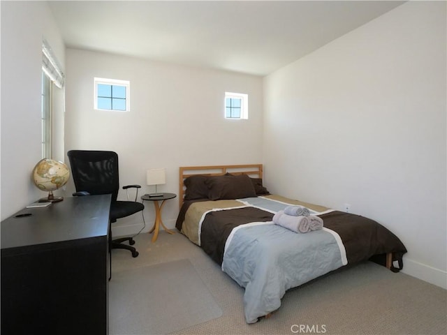 carpeted bedroom featuring baseboards and multiple windows