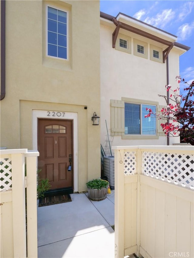 view of front of home with central air condition unit, fence, and stucco siding
