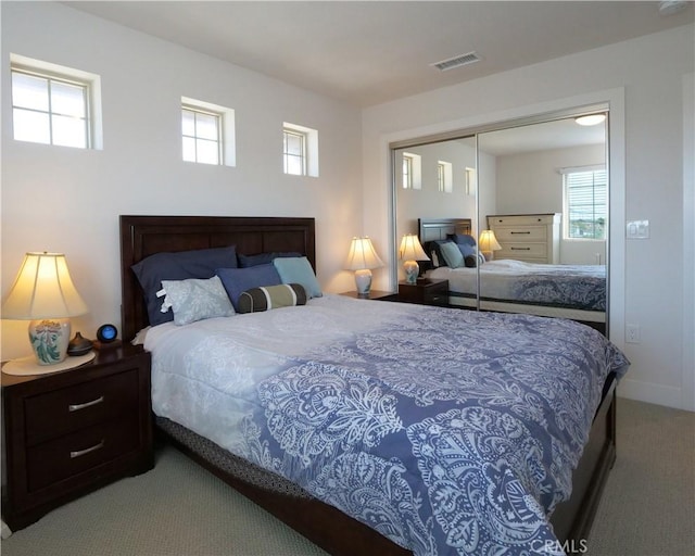 carpeted bedroom with visible vents, multiple windows, and a closet