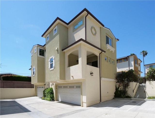 view of property with stairs, a garage, and stucco siding
