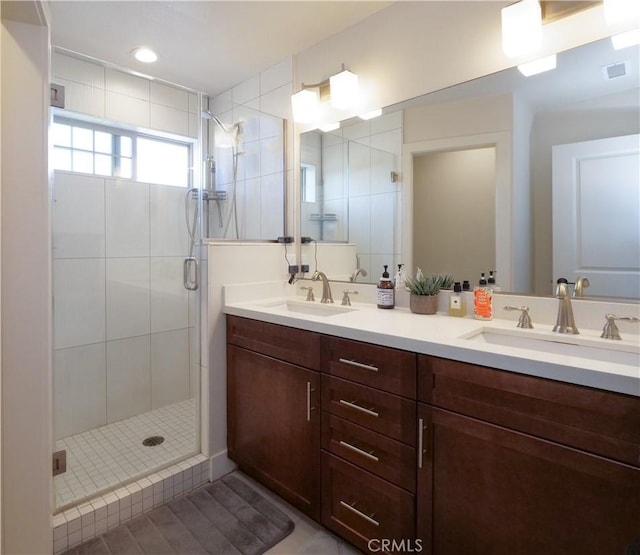 bathroom with a sink, a stall shower, double vanity, and visible vents
