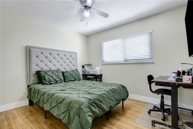bedroom with a ceiling fan, baseboards, and wood finished floors