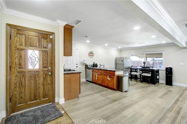 kitchen featuring visible vents, crown molding, light wood-style floors, a sink, and appliances with stainless steel finishes